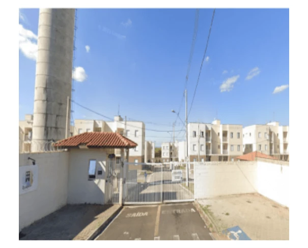 Apartamento em condomínio com portaria e bloqueio de veículos vista externa sob céu azul