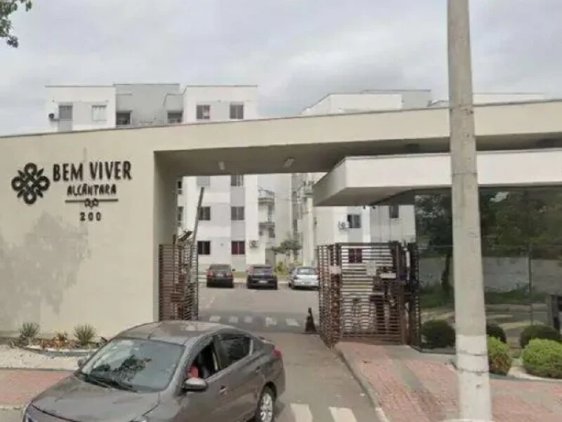 Apartamento branco no Condomínio Residencial Bem Viver Alcântara mostrando fachada e portaria com carro cinza na entrada