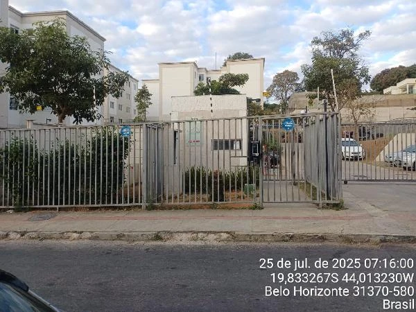 Apartamento branco de 2 quartos no condomínio com portão de ferro e área externa com árvores e veículos estacionados