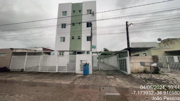 Apartamento branco e verde com 4 andares e grades brancas em fachada externa com calçada e rua frontal