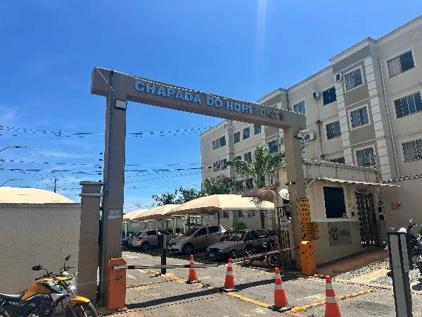 Apartamento de 40,6m² em condomínio com fachada clara e área externa com estacionamento e motos visíveis