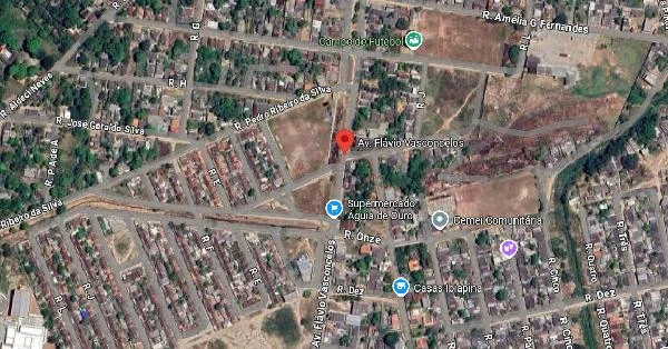 Imagem aérea mostrando área urbana com residências agrupadas, ruas pavimentadas e terrenos baldios ao redor