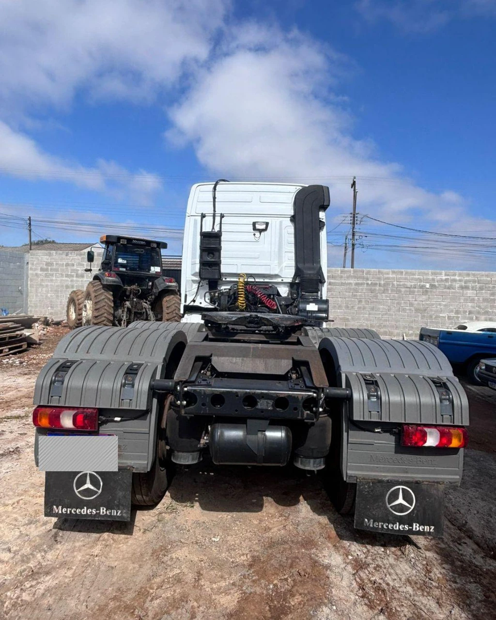 Caminhão trator branco Mercedes Actros 2546 LS 2020 visto de trás em pátio com solo de terra e parede de blocos