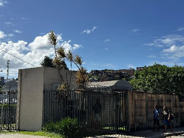 Apartamento 40m² com 2 quartos e portão metálico, localizado em condomínio residencial com muros altos e vegetação