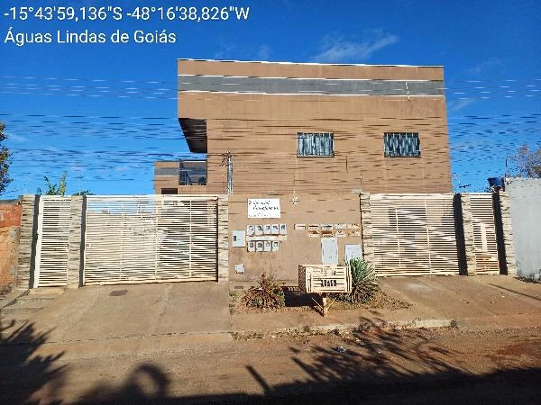 Apartamento com fachada de pintura marrom, portão branco de metal, janelas com grades, localizado em área urbana