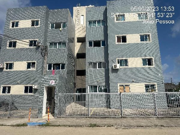 Apartamento cinza de 43m² em condomínio residencial com quatro andares e grade frontal em área urbana