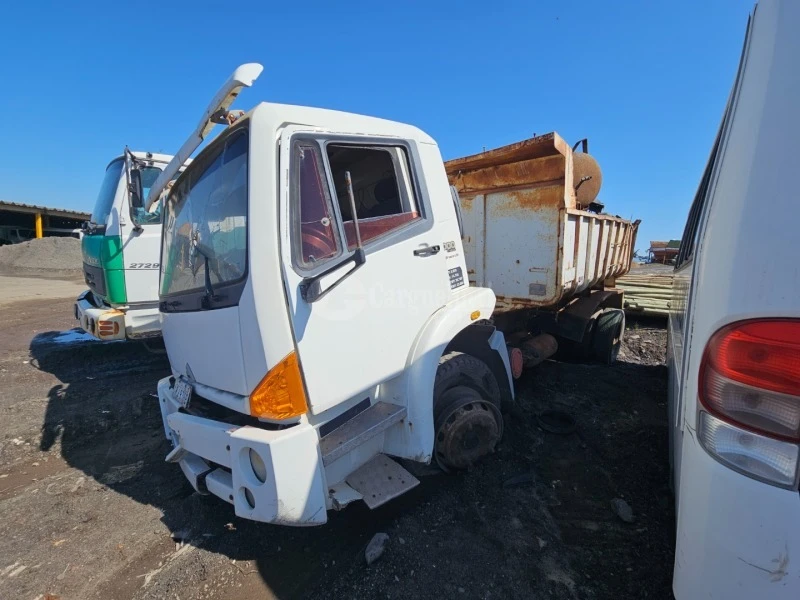 Caminhão branco Agrale 13000 com cabine danificada e caçamba enferrujada estacionado em pátio aberto