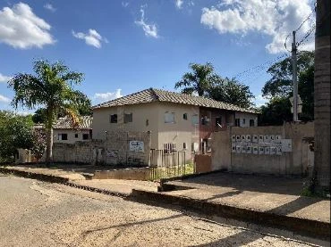 Apartamento em condomínio com fachada em pintura clara e telhado cerâmico visto da rua em dia ensolarado