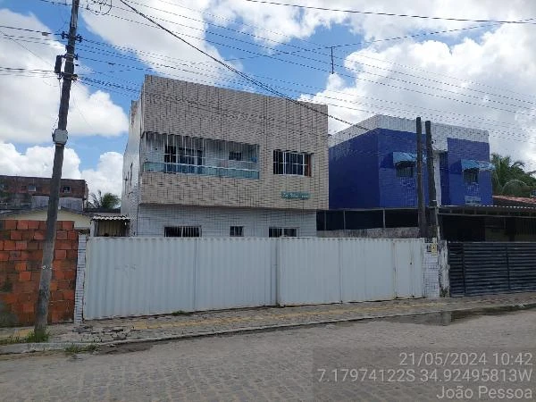 Apartamento branco em condomínio residencial com fachada de azulejos claros e portão branco em área urbana