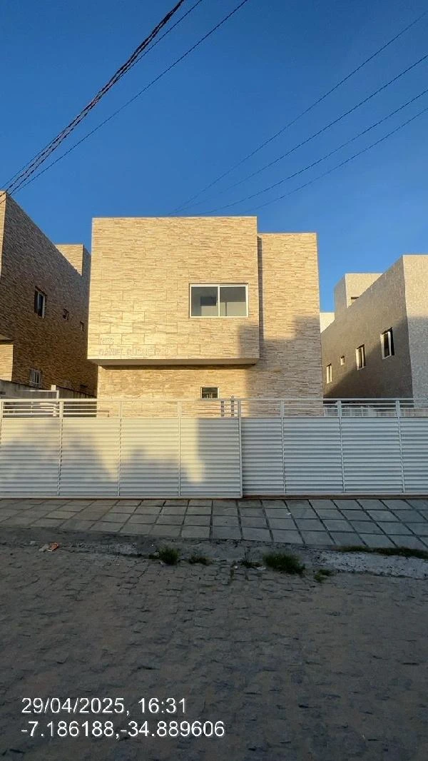 Apartamento bege com fachada em pedra e janela única, porteiro e muro branco em área urbana