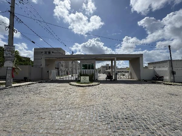 Entrada do condomínio residencial Floratta com portaria e área pavimentada sob céu com nuvens