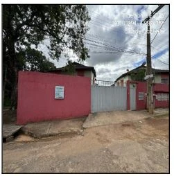 Apartamento com muro vermelho e portão branco em condomínio residencial com área externa e céu nublado