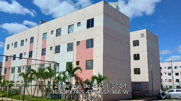 Apartamento bege em condomínio residencial com 3 andares, janelas retangulares, área externa com jardineiras e grades protetoras