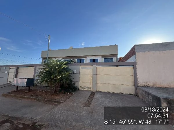 Apartamento branco com portão e muro baixo em área residencial, vista externa com alameda e calçada