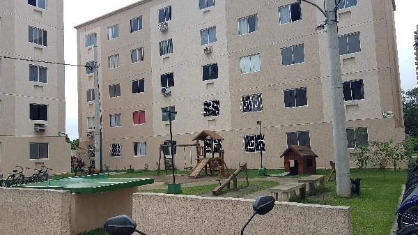 Apartamento bege em condomínio residencial com playground e área verde, várias janelas e estrutura em bom estado
