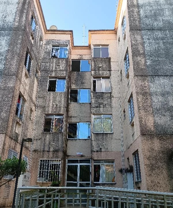 Apartamento com fachada de concreto e janelas padrão em condomínio residencial com quatro pavimentos e entrada principal com acesso por rampa
