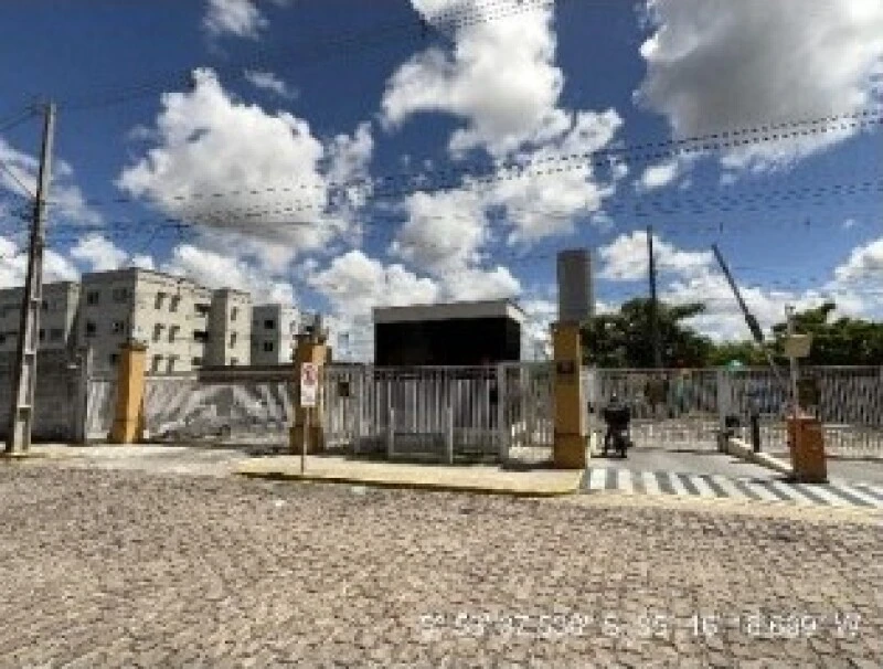 Apartamento com fachada em condomínio com portão metálico e calçamento em pedra no entorno