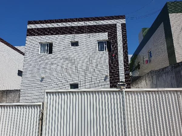 Apartamento com fachada revestida em azulejo preto e branco e portão branco em área urbana