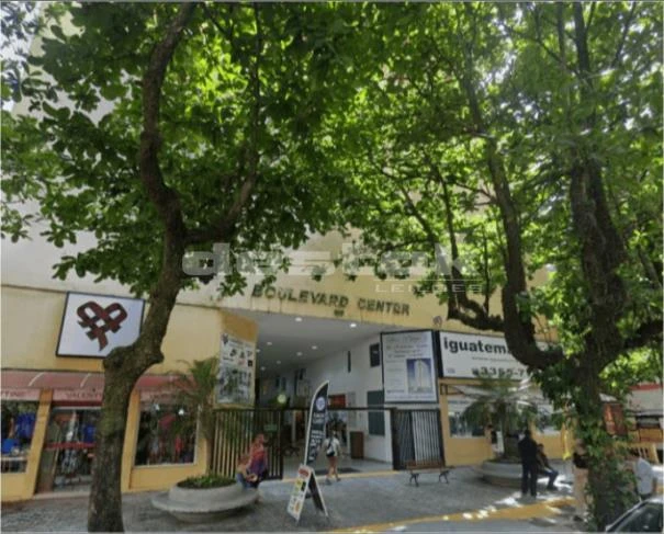 Apartamento com fachada amarela e árvores na frente no Condomínio Edifício Boulevard Center no Guarujá com entrada principal visível