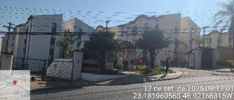 Apartamento branco no condomínio residencial com muros e portões, localizado em avenida movimentada, fachada sem avarias visíveis