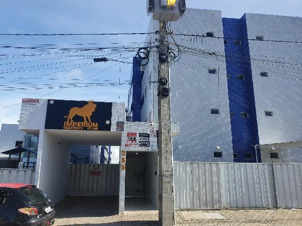 Apartamento branco e azul com fachada revestida em azulejos e estacionamento coberto em área urbana