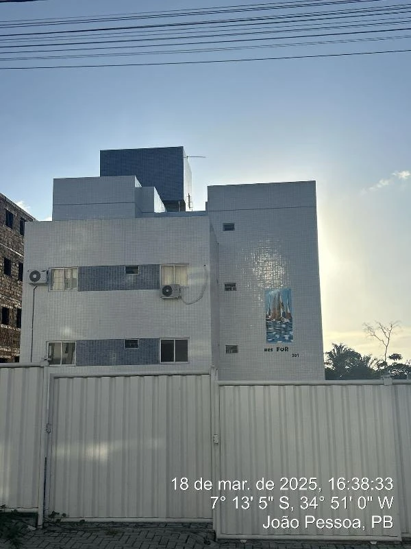 Apartamento em prédio branco com varanda e infraestrutura simples