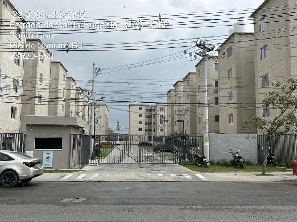 Apartamento bege com 2 quartos e 1 vaga em garagem no Residencial Jardim Jasmim com portão de entrada e área comum visíveis