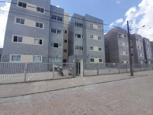Apartamento cinza em condomínio residencial com fachada revestida e portão de metal em via pavimentada
