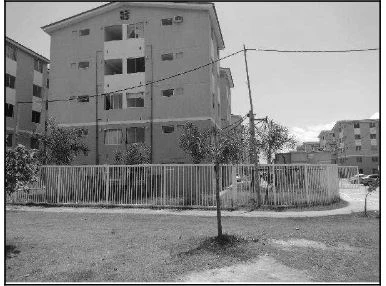 Apartamento bege em condomínio com cerca e área verde, fachada com janelas e varandas abertas sem avarias visíveis
