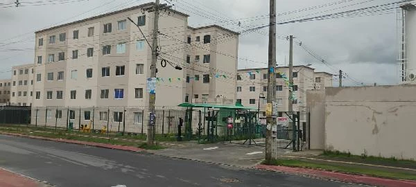 Apartamento bege em condomínio residencial com quatro pavimentos, fachada simples e portaria na entrada