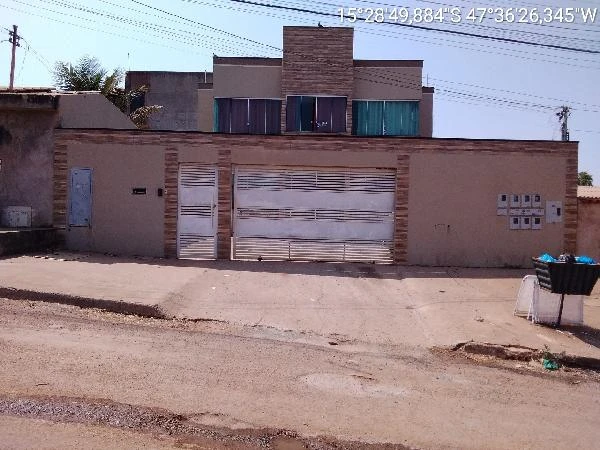 Apartamento com fachada bege e portão branco em condomínio residencial com área pavimentada na frente