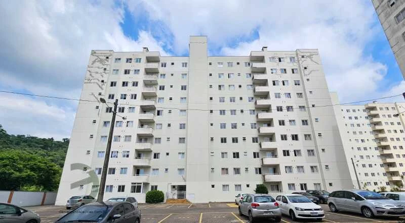 Apartamento branco em condomínio residencial com 7 pavimentos vista da fachada e vagas de garagem externas