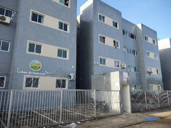 Apartamento cinza em condomínio residencial de 3 pavimentos com portão metálico e calçada na frente