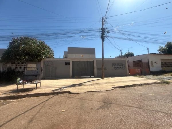 Apartamento branco com portão metálico no Condomínio Residencial Aldebaran XII em área urbana com calçada ampla