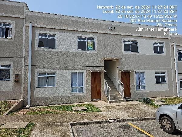 Apartamento bege de 2 andares com várias janelas, portas de madeira, área de estacionamento e parede externa em bom estado