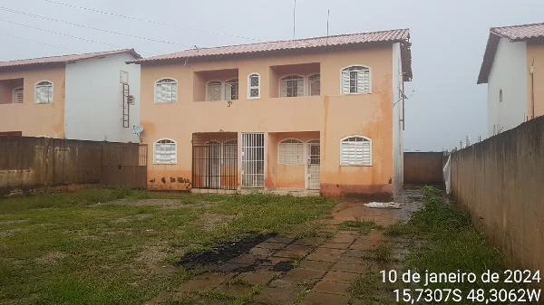 Apartamento em condomínio com pintura bege, duas entradas com grades e quintal gramado em área fechada