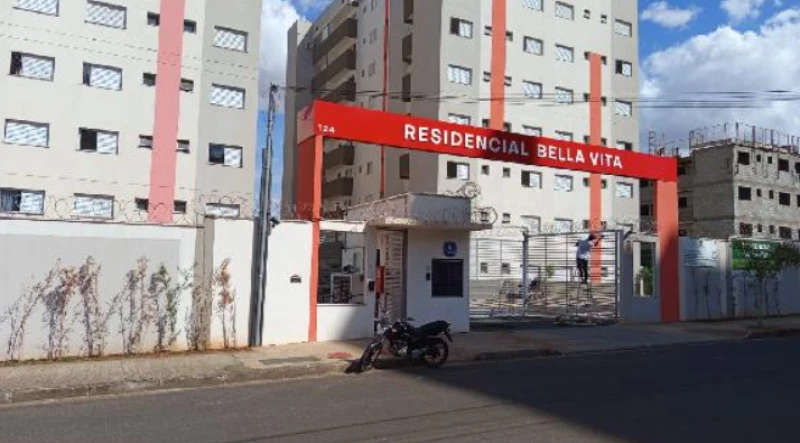 Apartamento de fachada branca e vermelha no Condomínio Residencial Bella Vita com portaria e motocicleta estacionada em frente