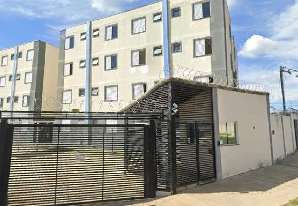 Apartamento cinza claro em condomínio residencial com portão preto de metal e grades de segurança no entorno