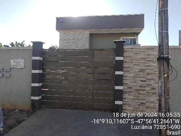 Apartamento cinza com portão metálico e muro em condomínio residencial em Luziania com fachada conservada