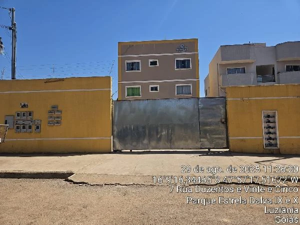 Apartamento amarelo em condomínio fechado com portão metálico e múltiplas unidades residenciais visíveis