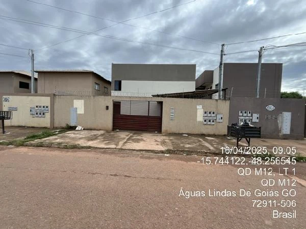 Apartamento branco com portão de metal vermelho em condomínio, fachada simples e rua sem movimento