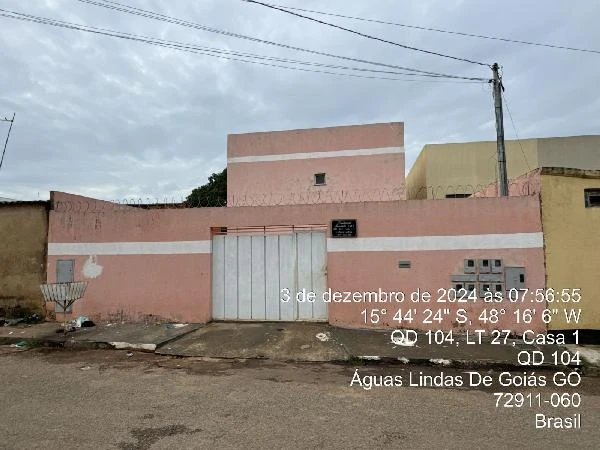 Apartamento com fachada rosa e portão branco em área urbana, com muro alto e sistema de segurança