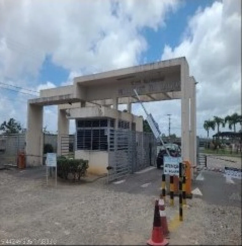 Entrada do condomínio Mirantes da Lagoa com guarita e cancela branca em área externa com céu parcialmente nublado
