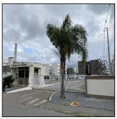 Apartamento branco de 52m² com portaria e portão de entrada em condomínio residencial numa rua pavimentada com céu nublado